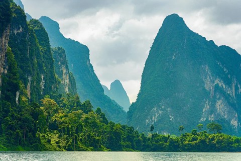 Misty mountain peaks covered in dense greenery under a cloudy sky, Cheow Lan Lake, Khao Sok