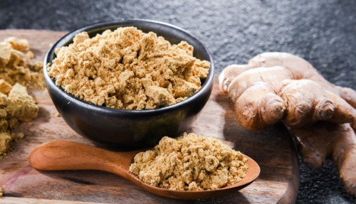 A bowl with ground ginger and its fresh rhizome