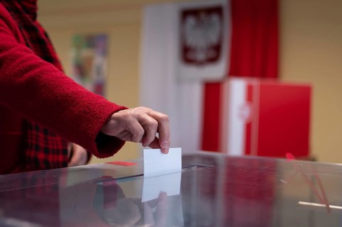 Voter's hand putting the vote into the ballot box.