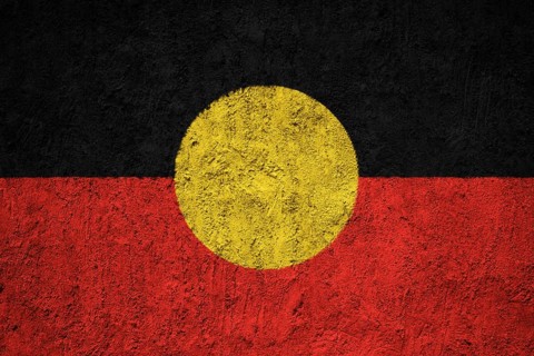 Australian Aboriginal flag painted on the cracked grunge concrete wall