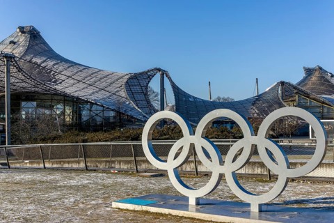 Sculptures of the Olympic rings and in the background the Olympic site with the Olympic buildings