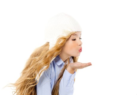 Beautiful winter kid girl blowing wind with lips isolated on white