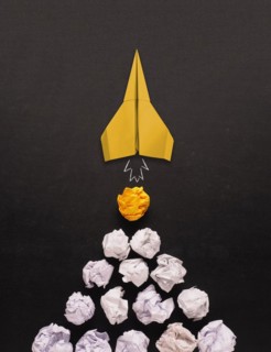 Launching paper rocket with jet stream of paper balls, creativity concept or new ideas metaphor,