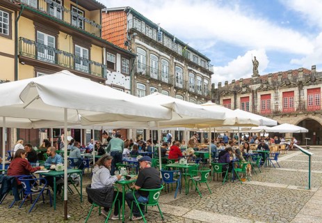 Tables and chairs, historic buildings in Largo da Oliveira square, city of Guimaraes, northern