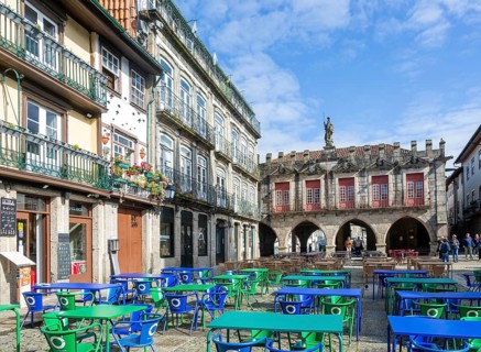 Tables and chairs, historic buildings in Largo da Oliveira square, city of Guimaraes, northern