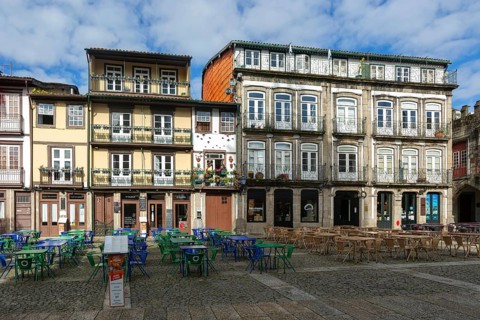 Tables and chairs, historic buildings in Largo da Oliveira square, city of Guimaraes, northern