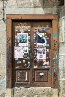 Stickers posters and graffiti tags on old wooden door, Guimaraes, Portugal, Europe