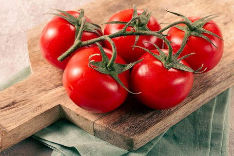 Fresh red tomatoes on a branch, on a wooden chopping board, close-up, no people