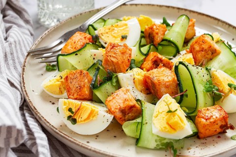 Delicious salmon and egg salad served on a plate with fresh cucumber and herbs for a healthy meal