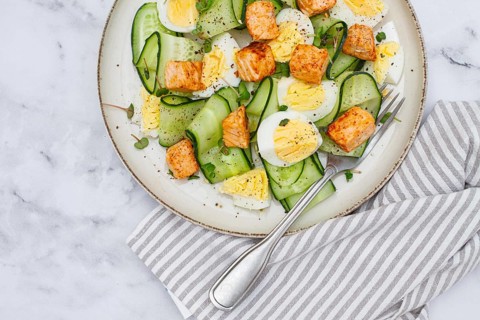 Delicious salmon and egg salad served on a plate with fresh cucumber and herbs for a healthy meal