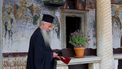 Priest with traditional robe in an interior with mural painting, Monastery of St John the