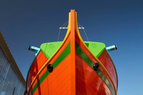 Close-up of the bow of a large orange boat in front of a clear sky, Diakofti boatyard, new