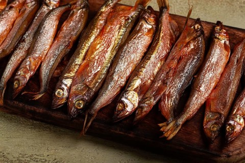 Cold smoked capelin, on a wooden chopping board, no people