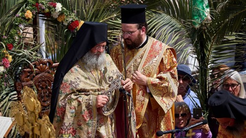 Two priests in rich robes stand in the middle of a solemn ceremony with religious symbols and