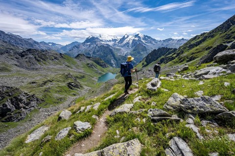 Mountaineer on hiking trail in mountain landscape, descent at Col du Louvie, view of mountain lake