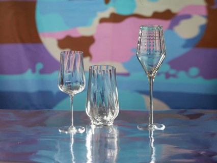 Various glasses on silver foil, behind them various colour elements, studio shot