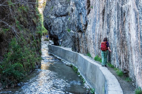 Woman on narrow hiking path Los Cahorros de Monachil, along the Rio Monachil river, narrow path in