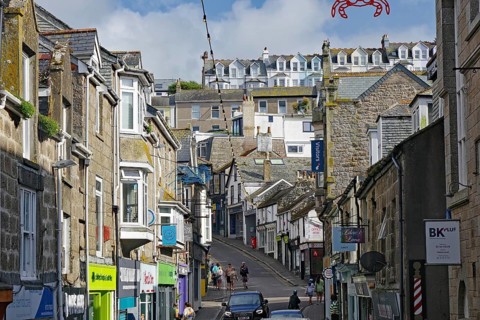A busy town street with traditional stone houses and many passers-by, holiday resort, St Ives,