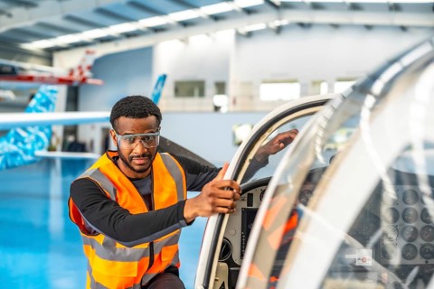 Aircraft maintenance engineer wearing safety glasses and a high visibility vest, performing a pre