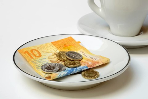 Tip, Swiss coins and Swiss franc note on plate, Switzerland, Europe