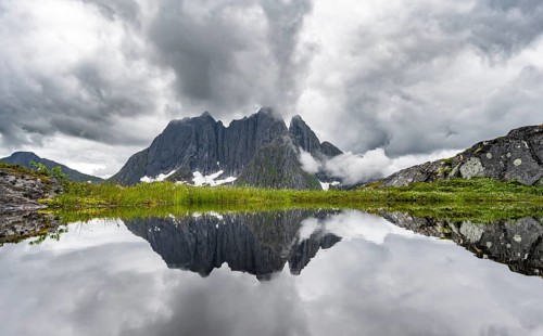Small lake in mountain landscape, hike to Mount Barden, reflection with mountain peak Breidtind,