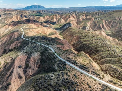 Winding road on a plateau, surrounded by colorful canyons and gorges, aerial view, Gorafe Desert,