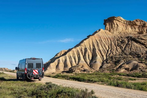 Colorful rock formation, camper van, semi-desert, Bardena Blanca area, Bardenas Reales Nature Park,