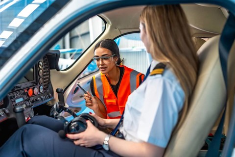 Aircraft maintenance engineer is explaining something to a pilot sitting in the cockpit of a small