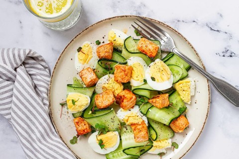 Delicious salmon and egg salad served on a plate with fresh cucumber and herbs for a healthy meal