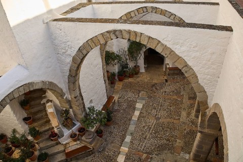 White courtyard with stone arches and plants in traditional style, Monastery of St John the
