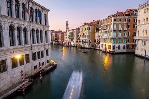 View of the Grand Canal with gondoliers at sunset, picturesque evening mood with illuminated