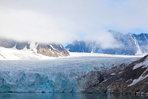 A fascinating glacier with snow-covered mountains and clouds creating a calm and peaceful