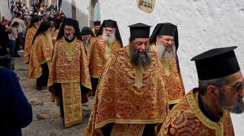 A group of priests in traditional gold and red robes walk during a procession, Orthodox ceremony,