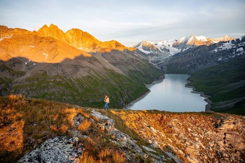 Mountaineer on the summit of Mont de la Blana, alpenglow at sunset, view of a blue mountain lake,