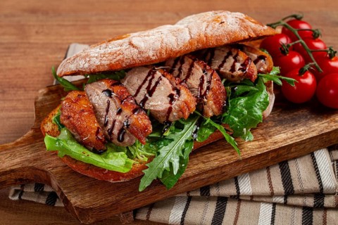 Sandwich with duck breast and arugula, balsamic sauce, on a wooden chopping board, breakfast,