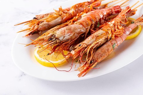 Freshly grilled prawns served, on a white platter, with lemon slices, for a delicious seafood