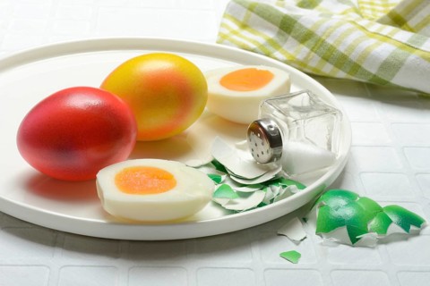 Easter eggs and salt shaker on plate, partially peeled