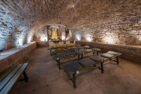 Stone vaulted cellar with benches and warm light, rustic and historic atmosphere, registry office,