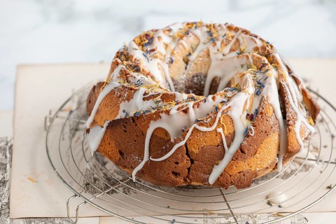 Marble bundt cake, cake with icing and edible flowers on a cake rack, light background
