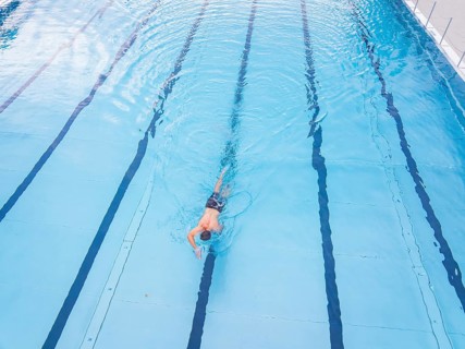 A person swims along the lanes in a large, blue swimming pool, outdoor pool Calw, Black Forest,