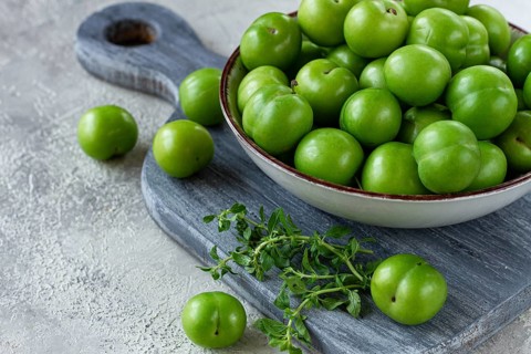 Tkemali, green cherry plum, in a bowl, on a gray table, top view, natural light, no people