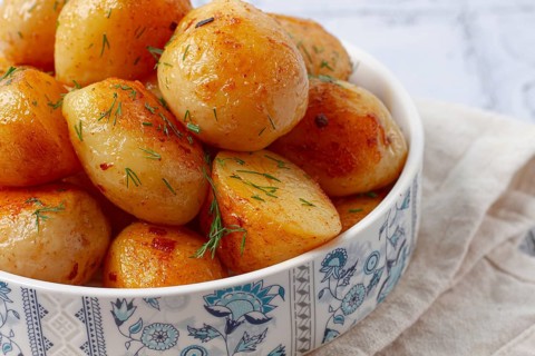 Baked new potatoes, with butter and dill, on a white plate, at home, no people