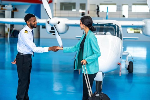 Pilot and businesswoman shaking hands in front of a private jet inside a hangar, finalizing their