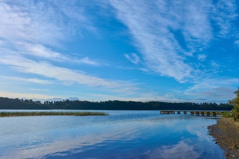 A long jetty on the shore of a calm lake under an overcast sky, Lake Mahinapua, Ruatapu, South