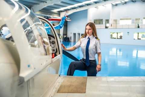 Confident female pilot boarding a small aircraft in a hangar, readying for an exciting flight and