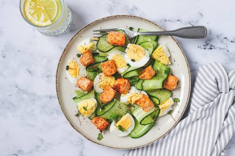 Delicious salmon and egg salad served on a plate with fresh cucumber and herbs for a healthy meal