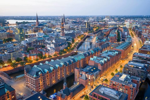 Aerial view of the Speicherstadt Hamburg at blue hour with churches and Alster in the background,