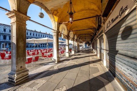 Chairs and tables of cafes, arcades at St Mark's Square in the morning light, Venice, Veneto,