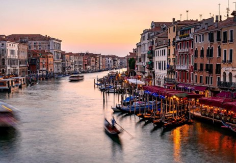 View of the Grand Canal with gondoliers at sunset, picturesque evening mood with illuminated