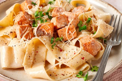 Tagliatelli pasta, with salmon slices and herbs, on a decorative plate, homemade, no people